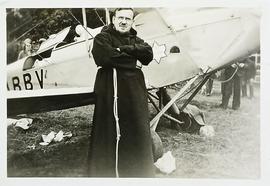 Fr. Senan Moynihan standing beside a biplane